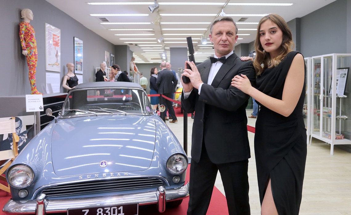 Bond-Double mit Bond-Girl vor dem Sunbeam Alpine S II